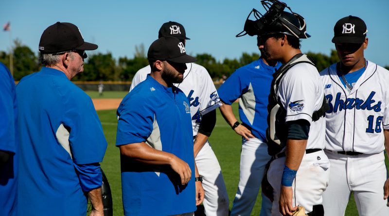 Assistant coach talking to catcher.