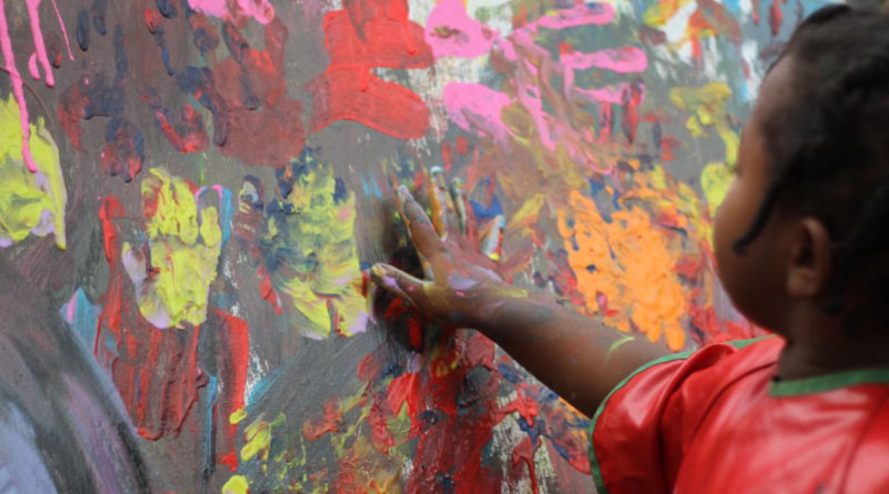 A little girl finger painting.