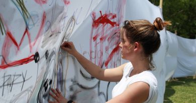 Student Stephanie Dovale painting on one the white sheets.