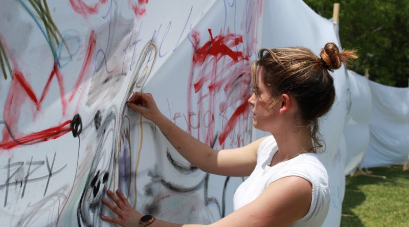 Student Stephanie Dovale painting on one the white sheets.